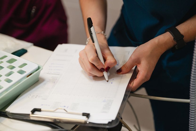 A veterinary team member writing up a patient chart on a clipboard.