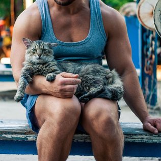 A man sitting outdoors with his cat.